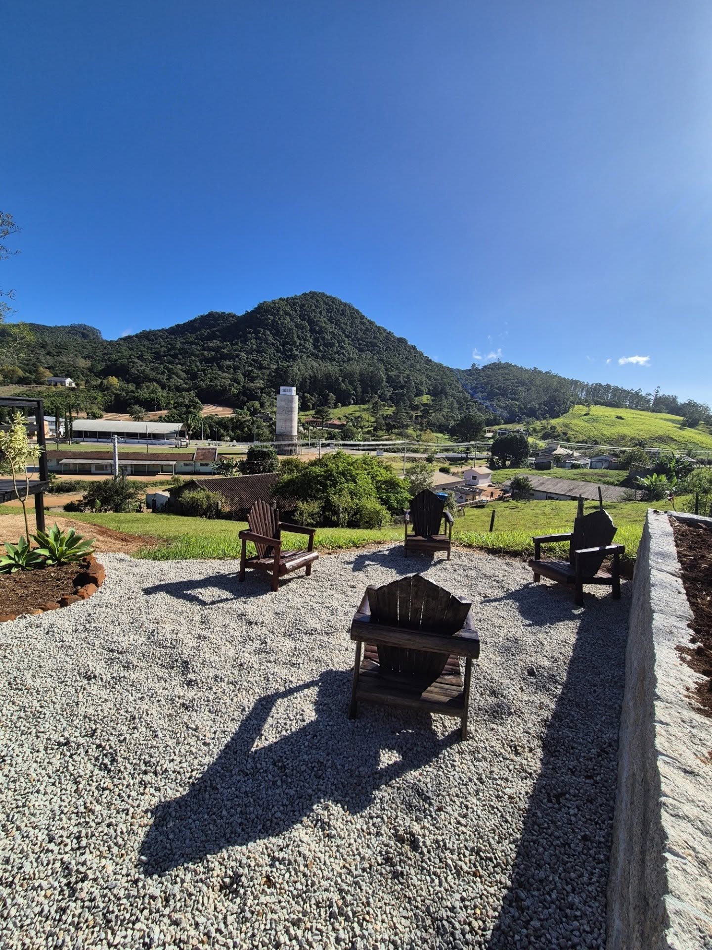 Área externa com cadeiras de madeira e vista para as montanhas