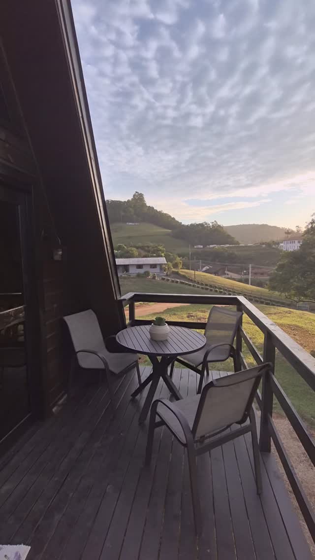 Varanda do chalé com mesa e cadeiras ao entardecer